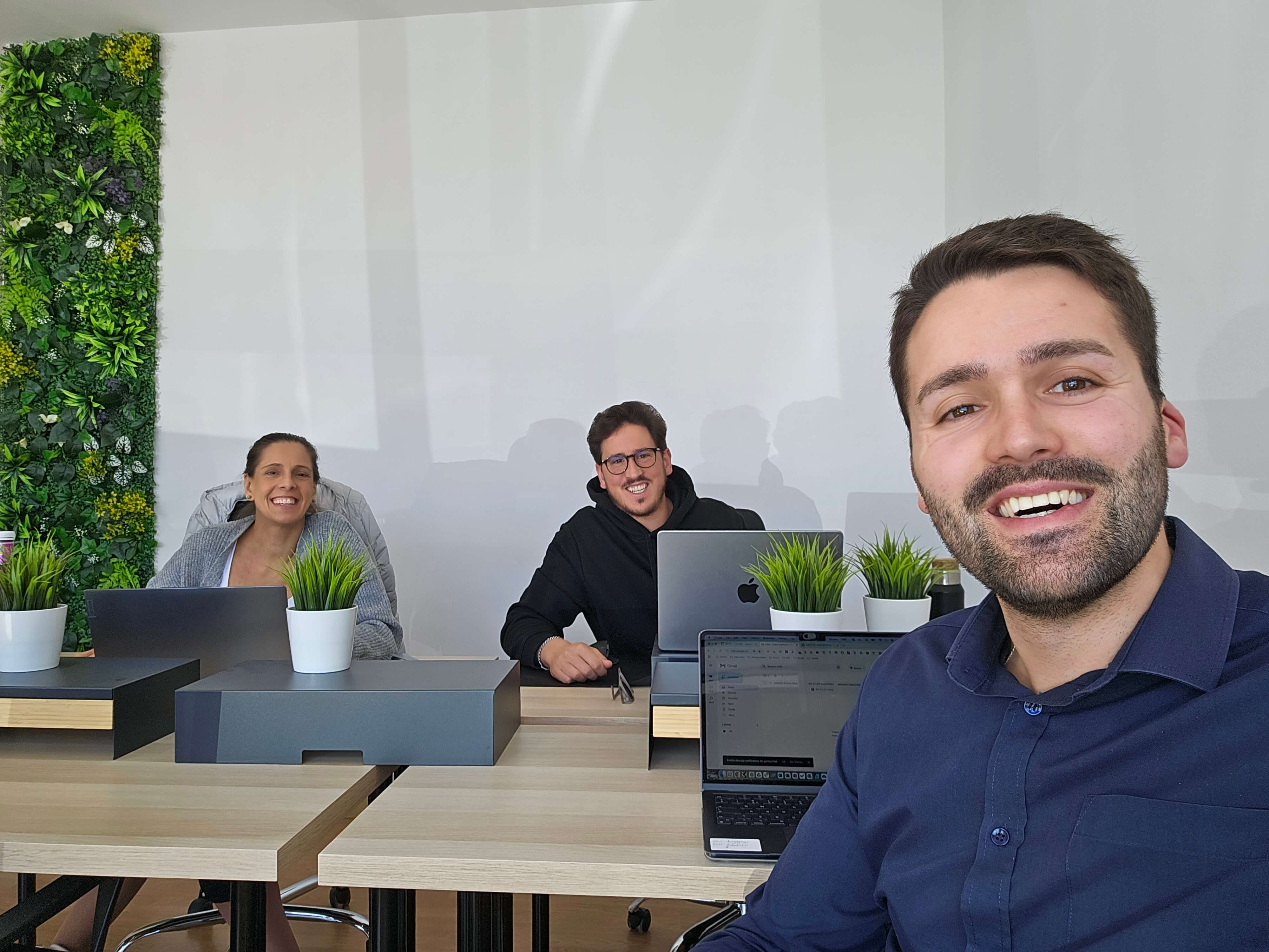 Equipa a trabalhar em ambiente colaborativo com parede verde