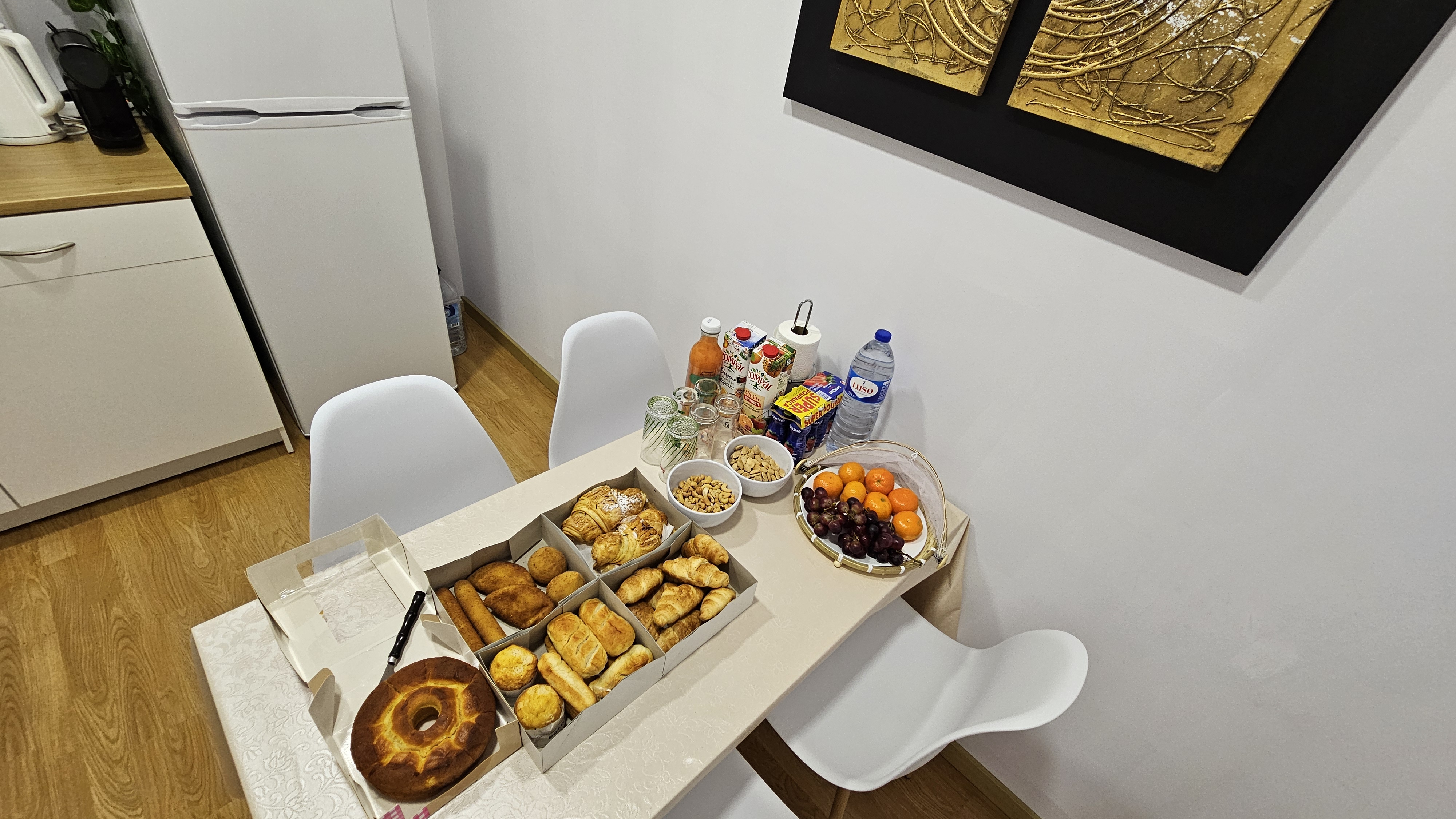 Pequeno-almoço — mesa da copa com caixa de pastelaria e fruta