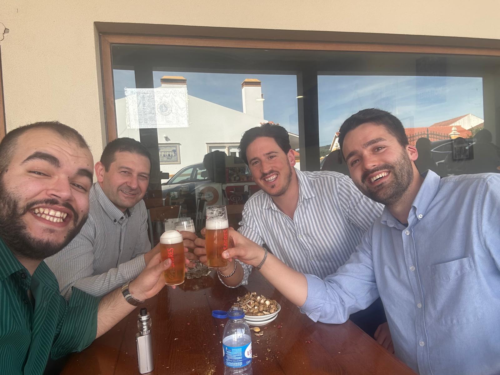 Brinde no café — quatro membros a brindar com cervejas